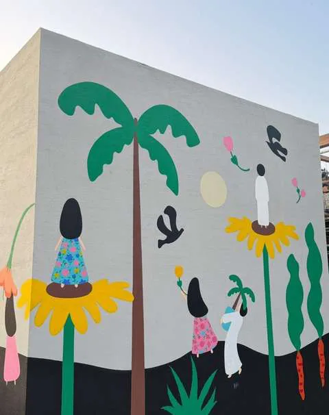 Mural of palm trees and figures on a public wall in Nad Al Sheba